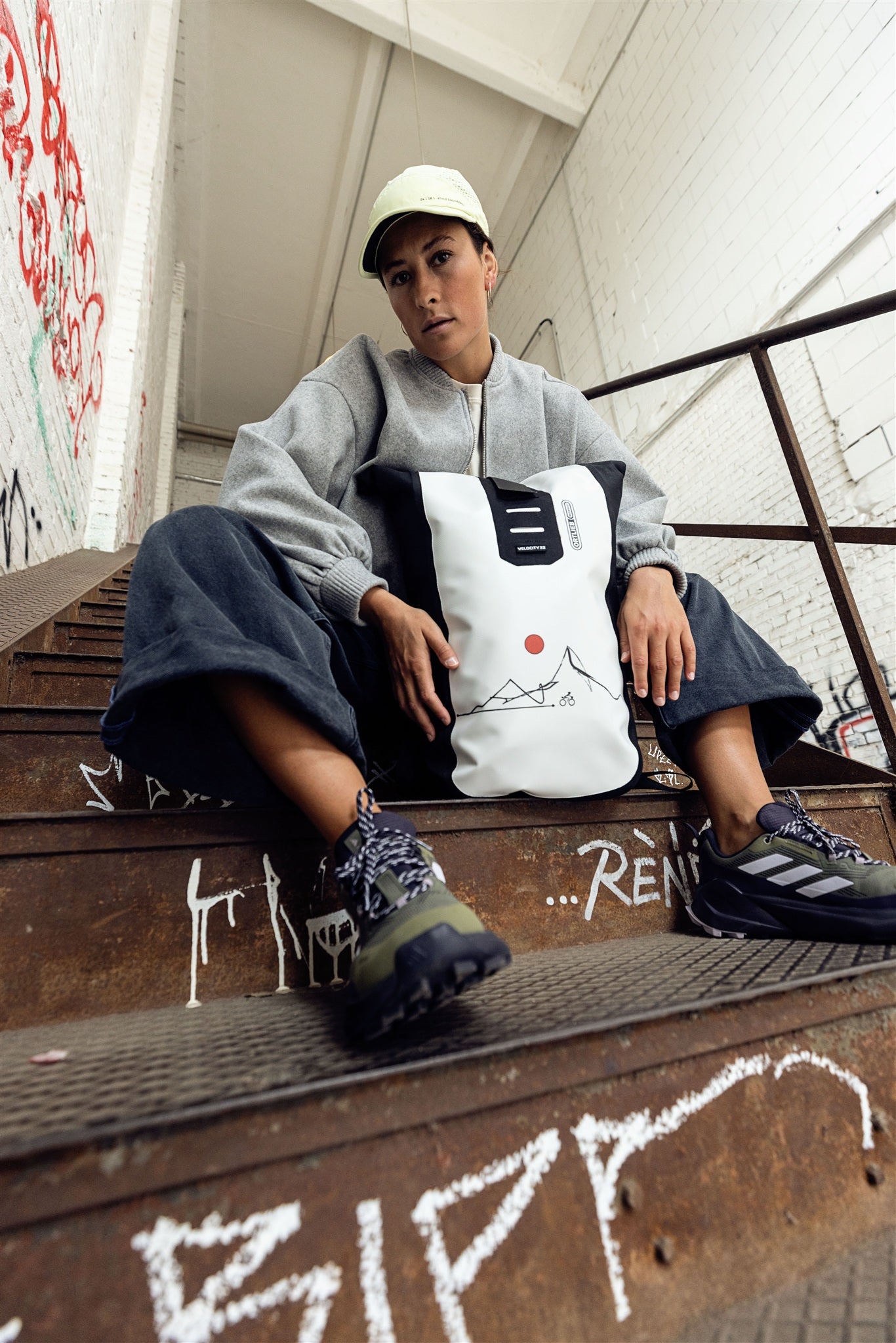 Person fährt Fahrrad in urbaner Umgebung mit weiß-schwarzem ORTLIEB Velocity Design Rucksack